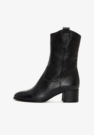 Botte en cuir noire mi-mollet avec surface texturée, bout arrondi, talon carré et languette de tirage en haut de la tige.