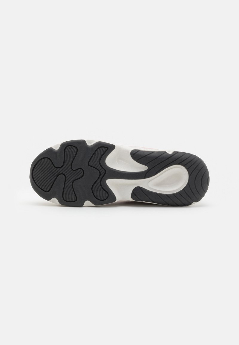 Suela de zapatilla con un diseño de goma negra ondulada, con patrones texturizados y una entresuela blanca. Talón redondeado y corte en la parte media para mayor flexibilidad.