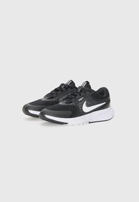 Baskets de course noires avec empiècements en mesh, logo swoosh blanc, semelle extérieure blanche contrastante et design de laçage texturé.