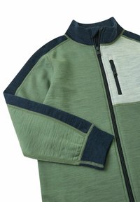 Grüne und marineblaue Zip-Jacke mit hohem Kragen, texturiertem Stoff, kontrastierenden Einsätzen und einer Brusttasche mit Reißverschluss.