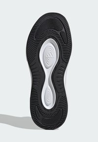 Sola di una scarpa sportiva in bianco e nero con una superficie texturizzata, schemi concentrici e una leggera curvatura nel design.