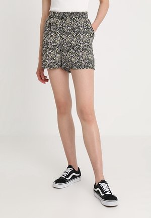 Shorts à imprimé floral avec un fond noir ; taille élastique ; poches latérales ; tissu léger ; associés à des baskets noires et blanches.