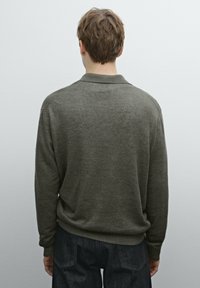 Donkergroen gebreid trui met een kraag en geribbelde manchetten en zoom, gezien vanuit de achterkant. Zachte textuur en comfortabele pasvorm.