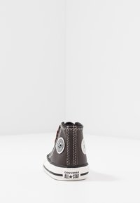 Czarne skórzane buty typu high-top z białą gumową podeszwą, okrągłymi naszywkami z logo, pomarańczowymi sznurówkami i kontrastowymi białymi przeszyciami.