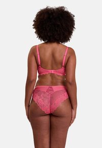 Ensemble de soutien-gorge en dentelle rose et string assorti avec des bords festonnés, des motifs floraux et un détail en découpe au centre du dos du string.