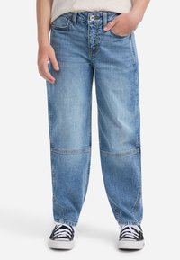 Jeans de mezclilla azul claro con un corte holgado, con cierre de botones, detalles de costura visibles y un dobladillo ligeramente desgastado. Combinados con zapatillas negras.