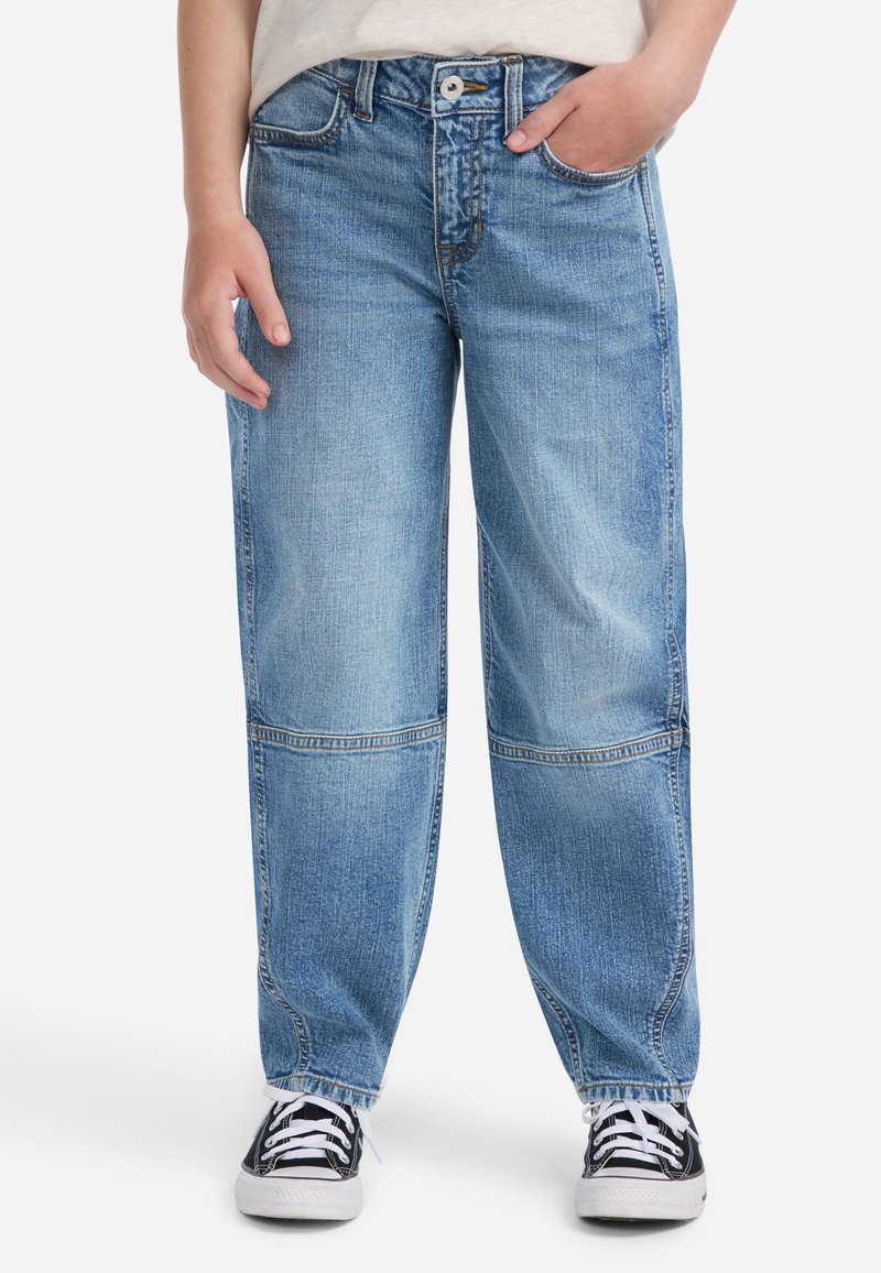 Jeans de mezclilla azul claro con un corte holgado, con cierre de botones, detalles de costura visibles y un dobladillo ligeramente desgastado. Combinados con zapatillas negras.