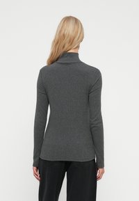 Hall grey värviline pikkade varrukatega turtleneck, mis on valmistatud pehmest materjalist. Sellel on kehafiguuri järgiv disain ja õmblusteta seljaosa, millel on peen ribitaoline tekstuur.