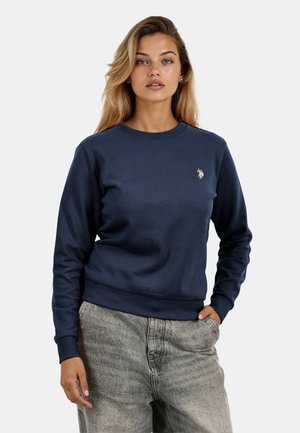 Navy blue sweatshirt made of soft fabric, featuring a crew neck, ribbed cuffs, and a small logo on the chest. Paired with light gray pants.