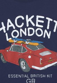 Námořnické tričko s červeným vintage autem nahoře s kajaky, bílý text "Hackett London" a "Essential British Kit GB."