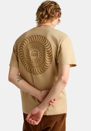Camiseta de algodón beige con un gráfico de espiral circular en tonos marrones y un patrón de tablero de ajedrez, con el logo "VANS" en el centro, de mangas cortas.