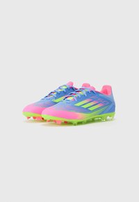 Bright blue and pink soccer cleats with green accents. Textured surface, six prominent studs, and a streamlined design for performance.