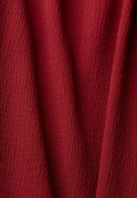 Tissu texturé écarlate avec une surface froissée, présentant une riche couleur rouge et un motif complexe, adapté à diverses applications textiles.