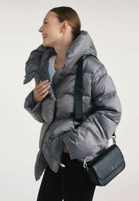 Szara kurtka puchowa z wysokim kołnierzem, zapięciem na zamek błyskawiczny i pikowanym wzorem. W zestawie czarna torba crossbody o gładkiej skórzanej powierzchni.