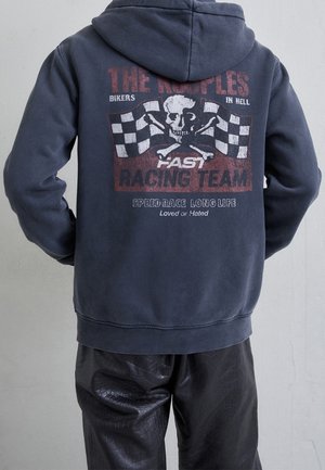 Sudadera navy con un gráfico de calavera y banderas a cuadros, con texto rojo y blanco que dice "EQUIPO DE CARRERAS" y "CARRERA RÁPIDA LARGA VIDA."