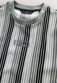 Gestreiftes Hemd in Schwarz, Grau und Weiß mit geriffelter Textur und Rundhalsausschnitt. Auf der Vorderseite ist "VENICE" aufgestickt.