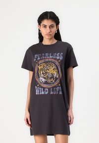 Melna T-kreklu kleita ar tīģera grafiku un tekstu "NEBAIDĪGA SAVVAĶA DZĪVE". Izgatavota no mīksta auduma, ar brīvu piegriezumu un īsām piedurknēm.