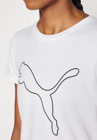 Valge lühikeste varrukatega T-särk, millel on ees suur must Puma logo disain. Pehme kangas ja ümmargune kaelus.