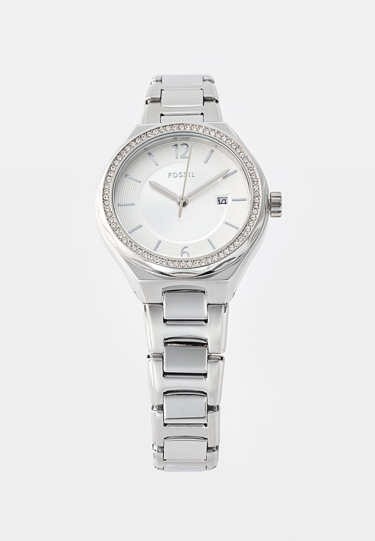 Orologio da polso in argento con cassa fossile, lunetta incastonata di cristalli, quadrante bianco, indicatori delle ore argentati e display della data su un bracciale a maglie metalliche.