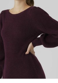 Mörklila stickad tröja med långa, puffiga ärmar och rund halsringning. Texturen är mjuk, med ett ribbat mönster över hela plagget.