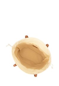 Ronde, crème canvas tas met bruine leren handvatten, trekkoordsluiting en een gladde binnenkant. Ontworpen voor veelzijdig opslaggebruik.