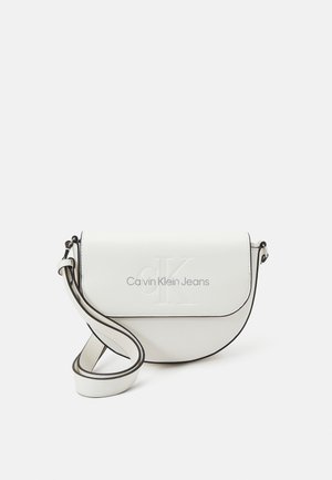 Biała torba na ramię w kształcie półksiężyca z regulowanym paskiem, logo Calvin Klein Jeans tłoczone na przedniej klapie.