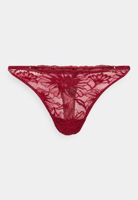 String rouge en dentelle florale avec un tissu en maille transparente, des coutures délicates et des bords festonnés, posé à plat sur un fond blanc.