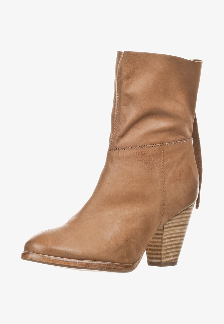 Bota de cuero marrón hasta el tobillo con puntera afilada y tacón apilado. Presenta un detalle de puño doblado y estrías verticales en el tacón.