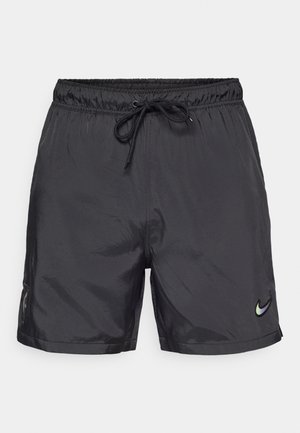 Shorts de sport noirs en tissu léger et brillant ; dotés d'une taille élastique avec un cordon de serrage et d'un petit logo au bas.