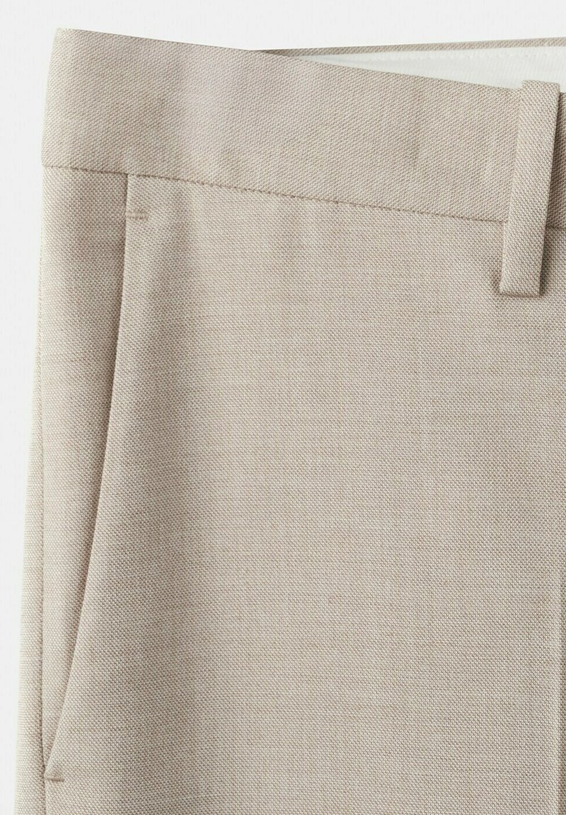 Beige stoffen broek met een tailleband en een zijplooi, met details van textuur en stiksels.