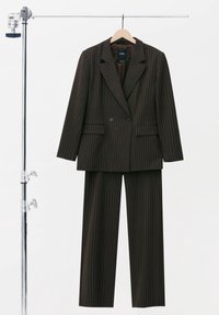 Mörkbrun randig kostym med en dubbelknäppt kavaj med två knappar, slagkrage och vida byxor, hängande på en galge.