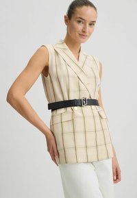 Beige ärmelloses Oberteil mit einem karierten Muster aus grünen und braunen Linien, einem Wickeldesign und einem schwarzen Gürtel mit einer dekorativen Schnalle.
