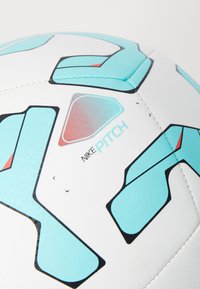 Nike Pitch -jalkapallo, jossa on valkoinen pinta, turkoosi ja musta geometrinen kuviointi, kuusikulmainen muotoilu ja teksturoitu pinta.
