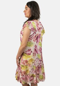 Vestido floral con patrones de hojas en rosa, verde y amarillo, mangas cortas de volante y dobladillo con volantes en capas. Tejido ligero.