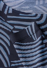 Tissu bleu et noir à motifs, comportant des rayures horizontales et verticales de largeurs variées, avec une texture côtelée et une apparence douce.