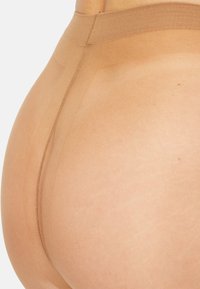 Shapewear beige con una texture liscia, design senza cuciture, vita alta e vestibilità aderente, che copre i fianchi e la parte bassa della schiena.