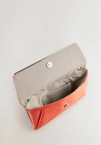 Bolso de mano color coral con un acabado suave y brillante. El interior cuenta con un forro beige y un cierre de metal a presión. Diseño compacto con un pequeño bolsillo.