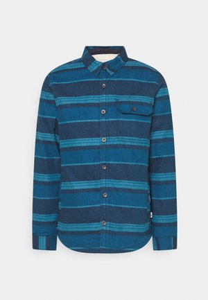 Long-sleeve button-up shirt in various shades of blue, featuring horizontal stripes, a chest pocket, and a rounded hem. Textured fabric.