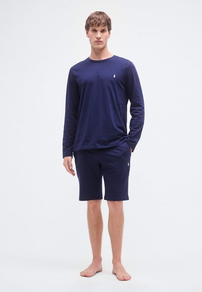 Camisa de mangas compridas azul-marinho e calções a condizer em tecido macio. Apresenta um logótipo no peito esquerdo e no bolso dos calções, com um corte descontraído.