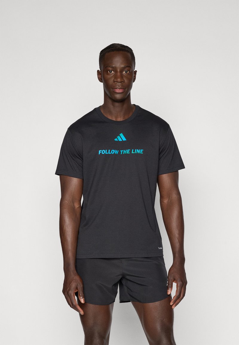 T-shirt de sport noir avec le texte "SUIVEZ LA LIGNE" en turquoise. Manches courtes, col rond et texture de tissu lisse.