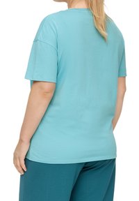 Helles Aqua Baumwoll-T-Shirt mit kurzen Ärmeln, Rundhalsausschnitt und entspannter Passform, kombiniert mit dunkeltürkisen Hosen, von hinten gezeigt.