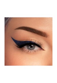 Primo piano di un occhio con una bold eyeliner blu a forma di ala, ciglia lunghe e un sopracciglio castano ben curato. L'iride è grigia.