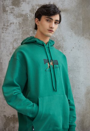 Groene hoodie van een zachte, gestructureerde stof. Heeft een voorzak, een capuchon met koordjes en een logo met een grafisch ontwerp op de borst.