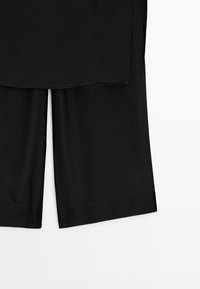 Sorte vidde bukser med kort ben og lige kant vist på en hvid baggrund.