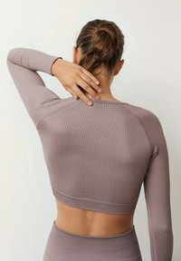 Prążkowany top z długim rękawem w stonowanym kolorze mauve o krótkim kroju, z zaokrąglonym dekoltem i dopasowanymi rękawami. Gładka, elastyczna faktura.