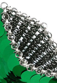 Grüner Paillettenstoff mit silbernen metallischen Kettengliedern, die eine strukturierte Form bilden. Die Textur ist glänzend mit kreisförmigen Mustern.