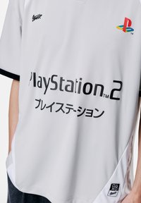 Grå trøje med sort "PlayStation 2" tekst og japanske tegn. Inkluderer multikolor PlayStation-logo og sorte ærmeaccenter.