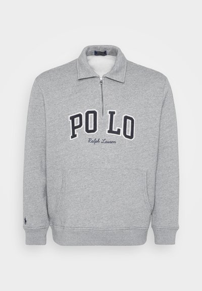 Szürke zipzáros pulóver, magas gallérral és tengerészkék hímzett "PO LO" felirattal az elején. Oldalsó zsebekkel és bordás mandzsettákkal rendelkezik.