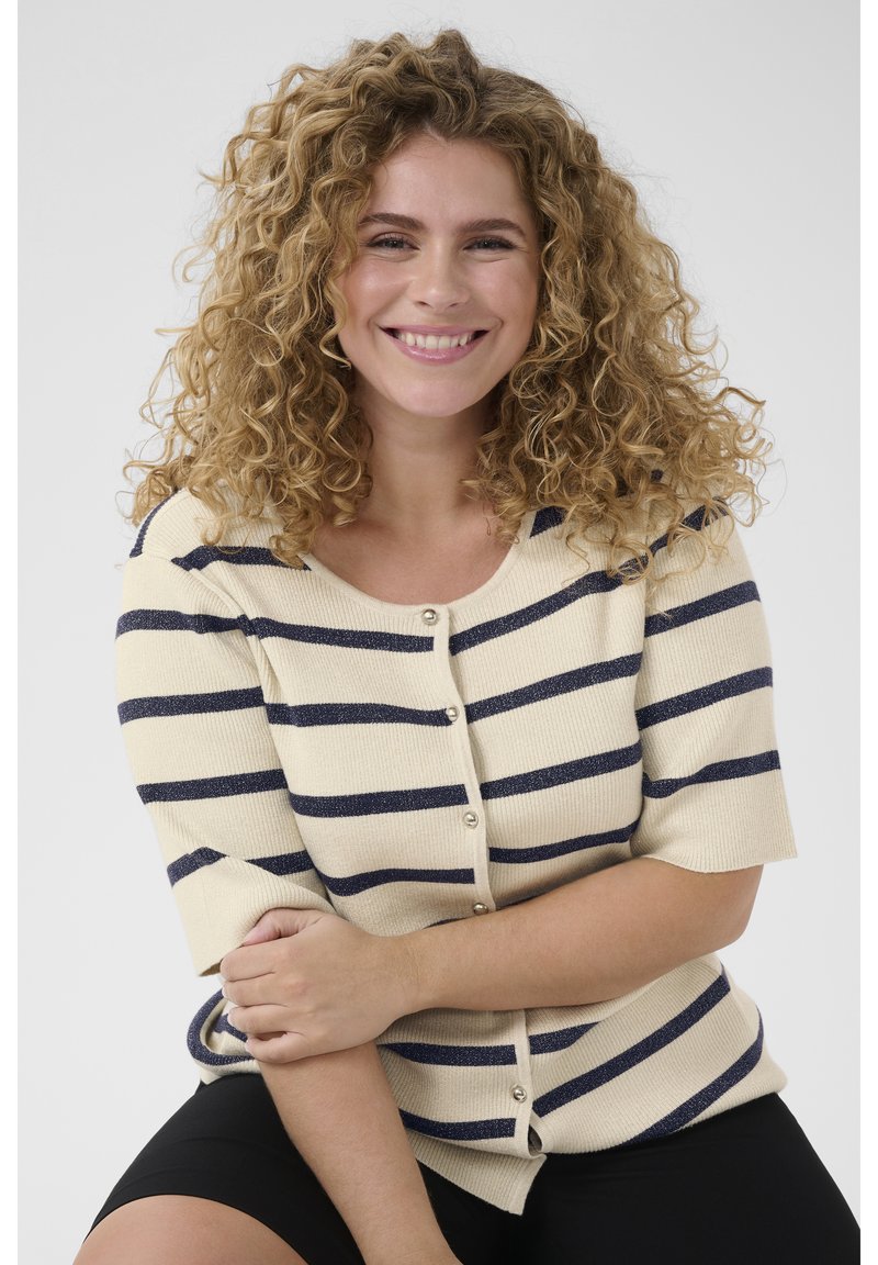 Beige strikket cardigan med marineblå vandrette striber, korte ærmer og knapper foran. Blød tekstur med ribstrikkede detaljer.