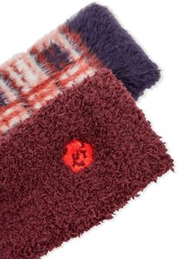 Tessuto strutturato e peloso in bordeaux e viola, con una sezione decorata in rosso, bianco e blu. Presenta un ricamo con dettaglio di un fiore rosso.